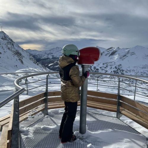 Skikind auf der Aussichtsplattform mit Fernglas sicht über Obertauern